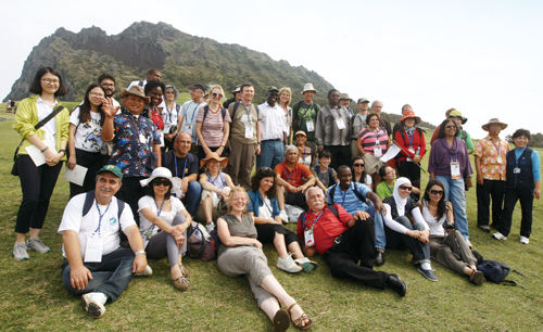 제주 생태투어에 나선 2012세계자연보전총회 참가자들이 성산 일출봉을 배경으로 기념촬영을 하고 있다.