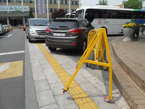 한 구청의 출입구에서 현관으로 이어지는 점자블록 보도 위에는 차량을 비롯 보행 방해물이 가로막고 있어 눈살을 찌푸리게 한다.