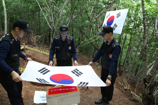 국방부 발굴 감식단 장병들이 무명용사의 수습한 유해를 태극기로 감싸고 있다.