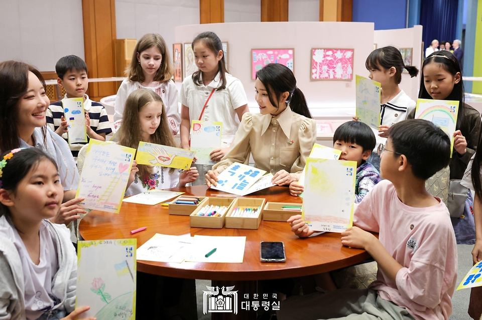 김건희 여사가 21일 청와대 춘추관에서 열린 ‘희망을 그리는 아이들: 우크라이나 아동 그림전’을 찾아 행사 참석 아이들과 메세지를 들고 기념 촬영을 하고 있다.