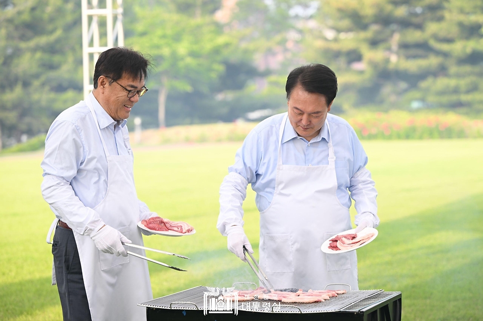 윤석열 대통령이 24일 서울 용산 대통령실 잔디마당에서 열린 ‘대통령의 저녁 초대’ 출입기자단 초청 만찬 간담회에서 정진석 비서실장과 함께 고기를 굽고 있다.