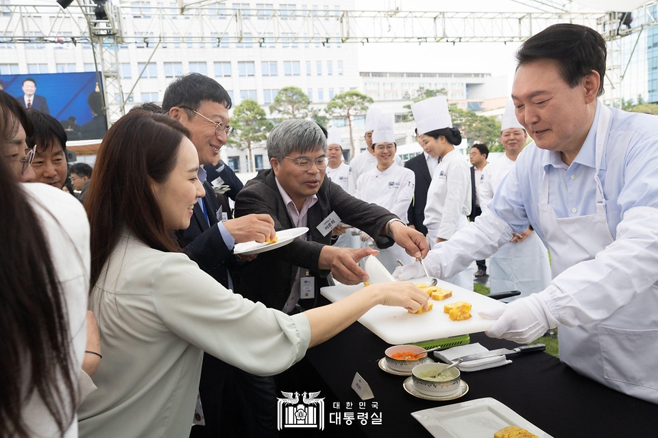 윤석열 대통령이 24일 서울 용산 대통령실 잔디마당에서 열린 ‘대통령의 저녁 초대’ 출입기자단 초청 만찬 간담회에서 취재진에게 계란말이를 배식하고 있다.