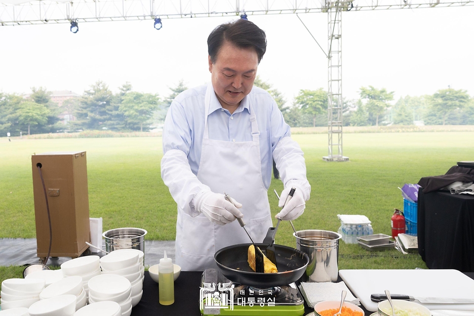 윤석열 대통령이 24일 서울 용산 대통령실 잔디마당에서 열린 ‘대통령의 저녁 초대’ 출입기자단 초청 만찬 간담회에서 계란말이를 만들고 있다.