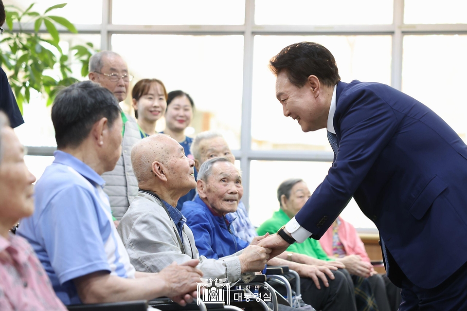 윤석열 대통령이 21일 경기도 수원시 수원보훈요양원을 방문해 ‘나라사랑 액자 만들기’ 체험활동 뒤 프로그램에 참여한 참전용사 및 전상·전몰군경 유족 어르신들과 인사하고 있다.