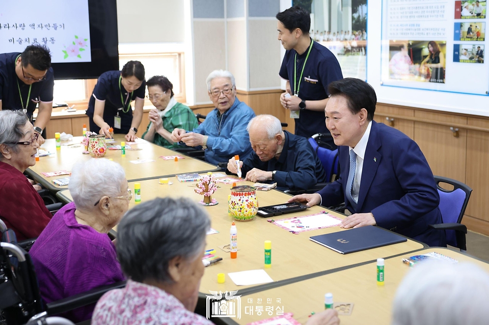 윤석열 대통령이 21일 경기도 수원시 수원보훈요양원 내 프로그램실에서 열린 ‘나라사랑 액자 만들기’ 체험활동에 참여해 참전용사 및 전상·전몰군경 유족 어르신들과 인사하고 있다.