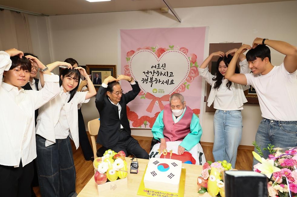 한덕수 국무총리가 21일 수원시 장안구 보훈공단 보훈원을 방문해 오성규 애국지사 등 보훈원 입소자들을 위문하며 청년 인턴들과 101번째 생일을 맞은 오성규 지사를 축하하고 있다.