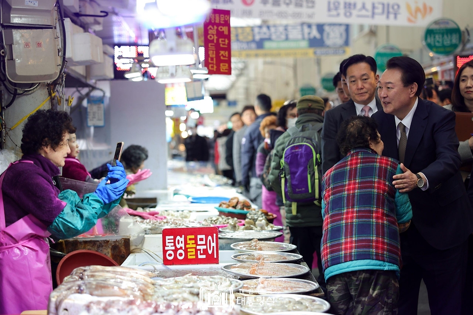 윤석열 대통령이 22일 경남 창원시 마산합포구 마산어시장을 방문해 상인들과 인사를 나누고 있다.