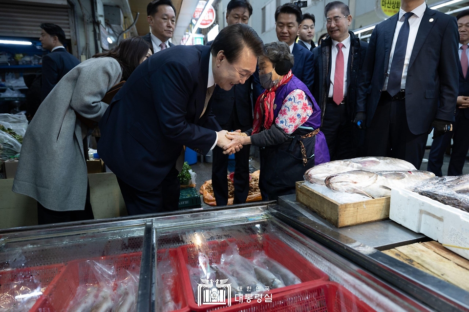 윤석열 대통령이 22일 경남 창원시 마산합포구 마산어시장을 방문해 상인들과 인사를 나누고 있다.