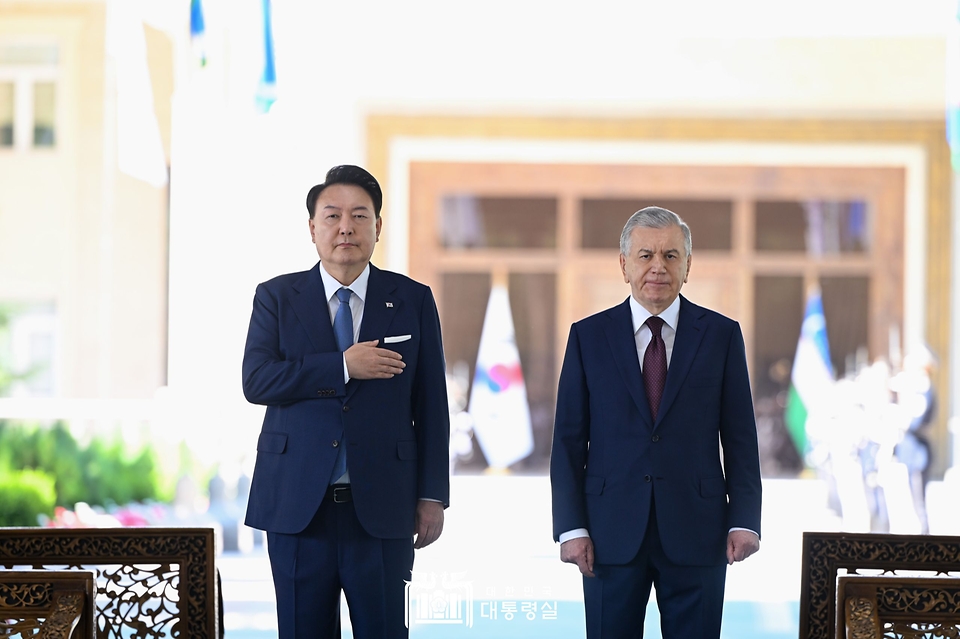 윤석열 대통령이 14일(현지시간) 우즈베키스탄 타슈켄트 대통령궁에서 열린 공식환영식에서 샤브카트 미르지요예프(Shavkat Mirziyoyev) 우즈베키스탄 대통령과 사열대에 올라 애국가 연주 때 가슴에 손을 얹고 있다.