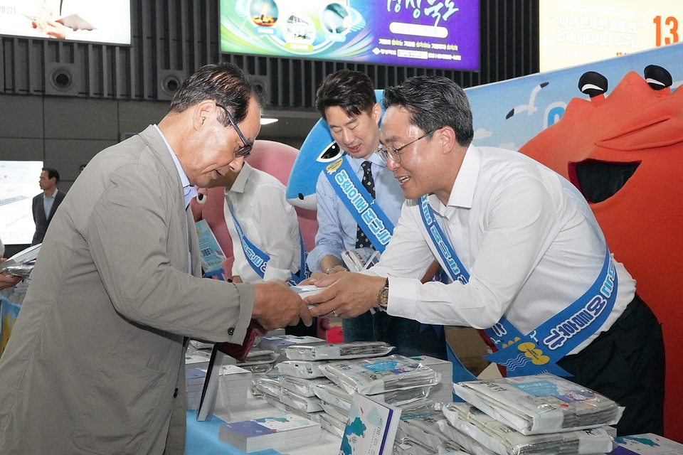 강도형 해수부 장관이 16일 서울 강남구 수서역에서 열린 ‘여름휴가 어촌에서 보내기 캠페인’에서 책과 김을 나눠주고 있다. 