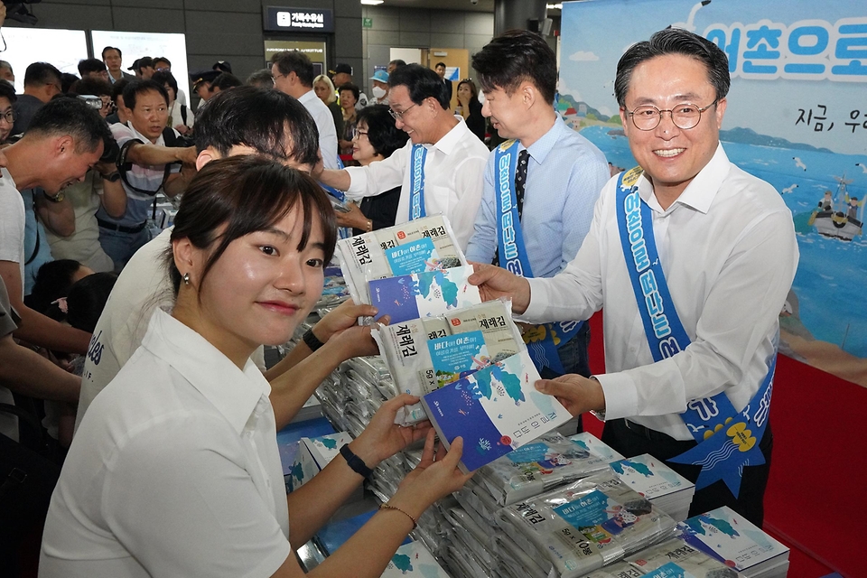 강도형 해수부 장관이 16일 서울 강남구 수서역에서 열린 ‘여름휴가 어촌에서 보내기 캠페인’에서 책과 김을 나눠주고 있다. 