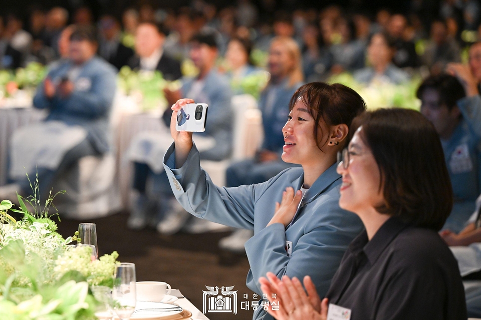 참가 선수가 22일 서울 중구 신라호텔에서 열린 ‘2024 파리올림픽 선수단 격려 행사’에서 축하공연을 핸드폰으로 촬영하고 있다.