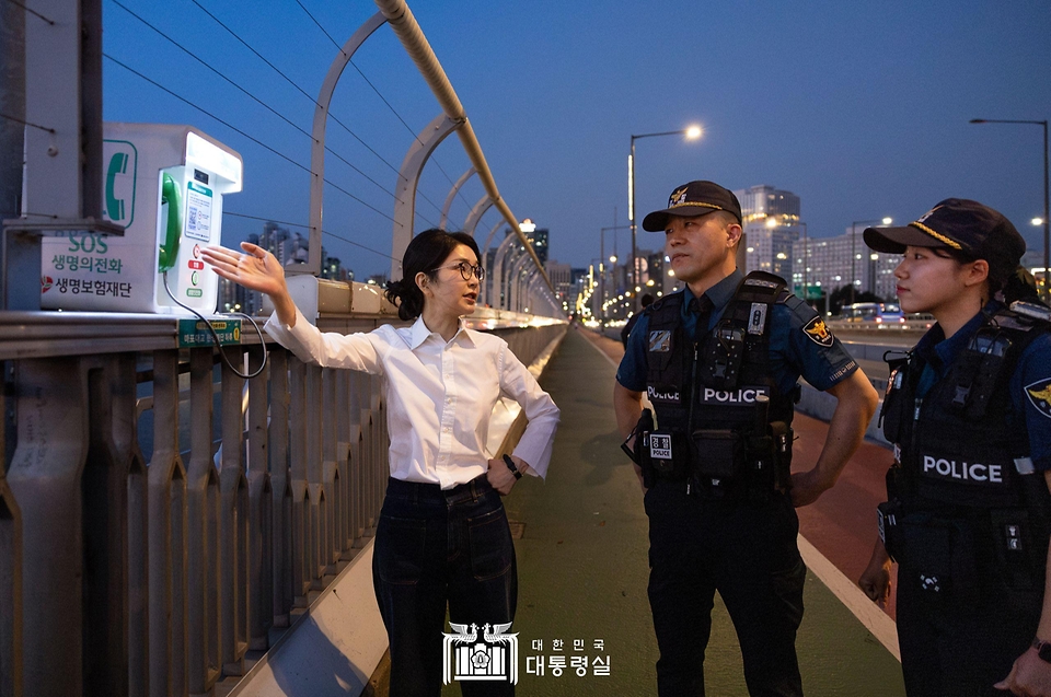 김건희 여사가 10일 ‘세계 자살 예방의 날’을 맞아 서울 마포대교에서 마포경찰서 용강지구대 근무자와 함께 ‘생명의 전화’를 살펴보며 대화하고 있다.