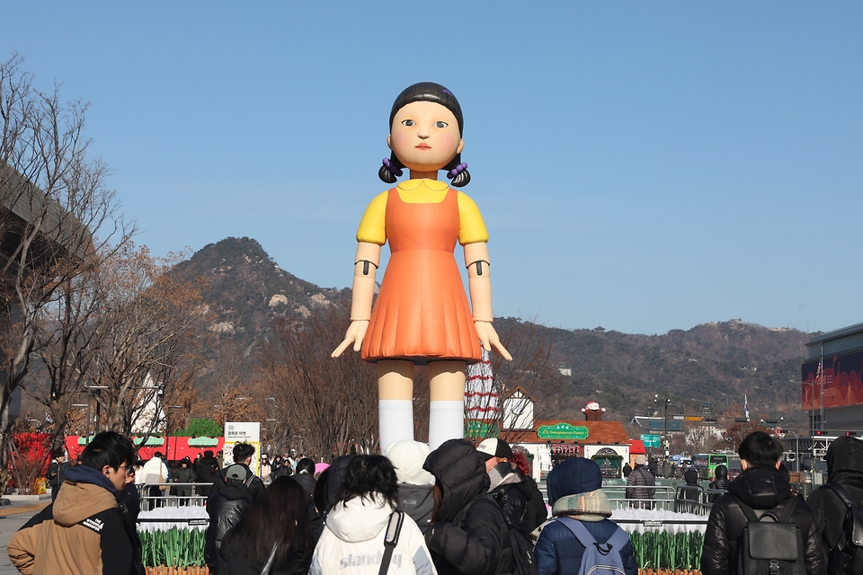 27일 서울 광화문광장에 마련된 ‘오징어게임 시즌2’ 영희 조형물 앞에서 외국인 관광객들이 기념 사진을 찍고 있다.