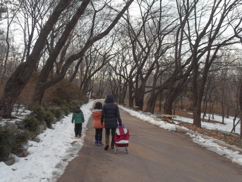 어린이대공원 산책로를 걷고 있는 가족, 노변에 흰눈이 쌓였다. 지난 겨울의 추억을 담았다.