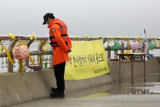 팽목항 등대 앞에서 한 소방관이 바다를 바라보고 있다. 팽목항 곳곳에는 모든 실종자가 가족의 품으로 돌아갈 수 있는 플래 카드가 걸려 있다.(사진=저작권자 (c) 연합뉴스. 무단전재-재배포금지)