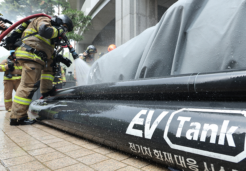 소방관들이 전기차량에서 화재가 발생한 상황을 가정한 훈련에서 전기차 화재 대응 시스템(EV Tank)을 활용해 불을 끄고 있다. (사진=저작권자(c) 연합뉴스, 무단 전재-재배포 금지)