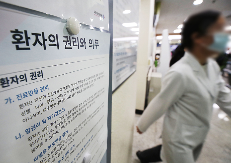 의대정원 증원에 반대하는 전공의들의 집단 행동이 이어지고 있는 13일 서울시내 병원에서 한 의료진이 ‘환자의 권리와 의무’ 게시물 앞을 지나고 있다. (ⓒ뉴스1, 무단 전재-재배포 금지)