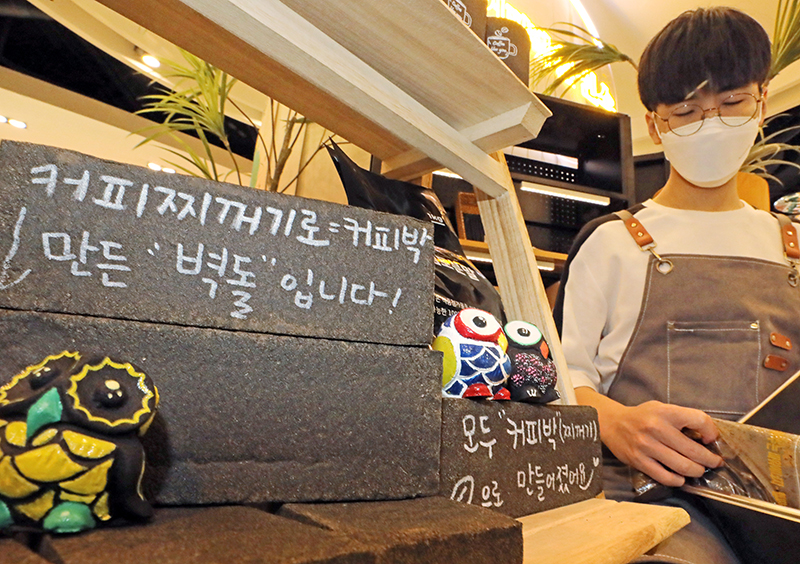 서울시 마포구 현대백화점 신촌점에 위치한 커피박환전소에서 직원이 커피찌꺼기(커피박)를 재활용한 인테리어 소품 옆에서 커피찌꺼기를 모으고 있다. (ⓒ뉴스1, 무단 전재-재배포 금지)