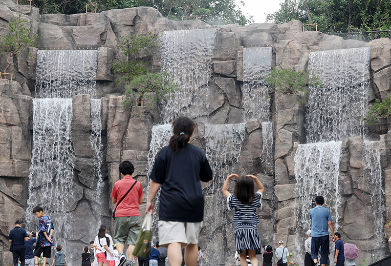 서울 동대문구 배봉산 숲속 폭포를 찾은 시민들이 시원하게 쏟아지는 물줄기를 바라보며 더위를 식히고 있다. (ⓒ뉴스1, 무단 전재-재배포 금지)