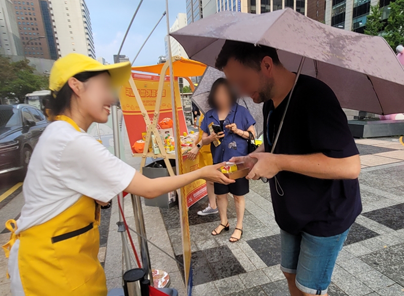 외국인이 우리 쌀로 만든 주먹밥과 식혜를 받고 있다.