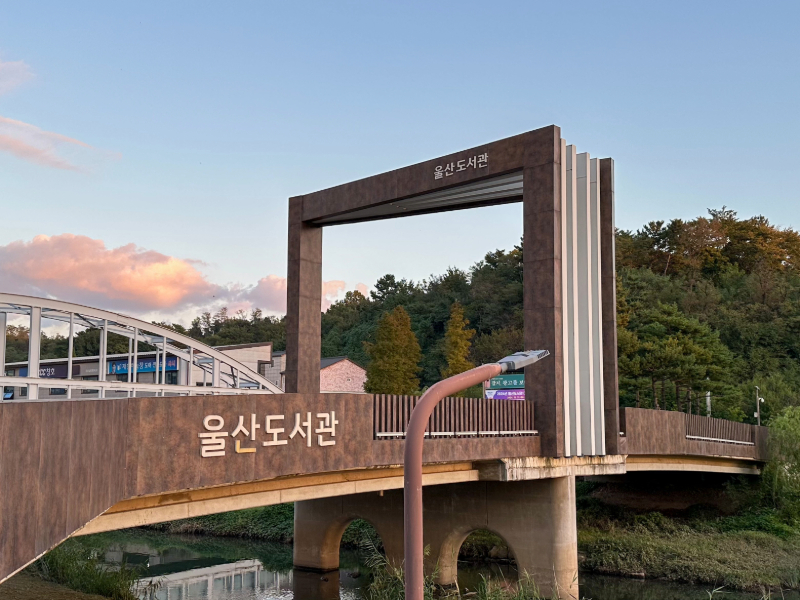 울산도서관 입구 전경. 여천천 위로 놓인 다리와 책 모양의 구조물.