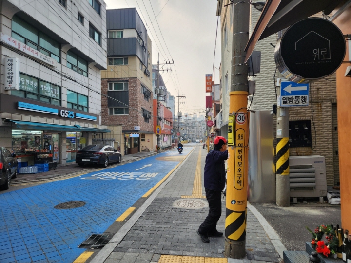 상가가 많은 성자초등학교 주변의 차도와 보도가 확연히 구분되어 있다. 파란색 노면이 차도라는 것을 알 수 있다.