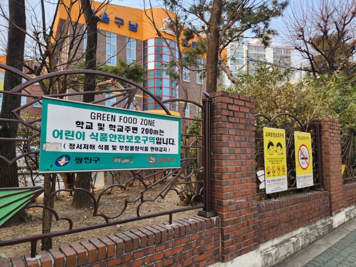 학교 담벼락에 어린이 식품안전구역, 교육환경보호구역, 학교금연구역을 알리는 경고문이 붙어 있다.