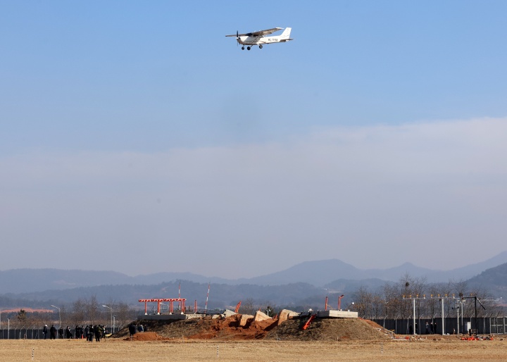 12·29 제주항공 여객기 참사 60일째인 26일 오후 전남 무안국제공항에서 교육용 훈련기가 항공철도사고조사위원회, 경찰, 국과수 관계자들이 현장 조사하고 있는 방위각 시설(로컬라이저) 위를 날고 있다. 2025.2.26. (ⓒ연합뉴스, 무단 전재-재배포 금지)